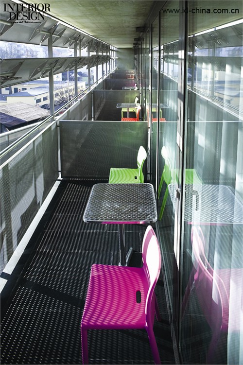 色彩濃烈的椅子與露臺的灰色調(diào)對比。